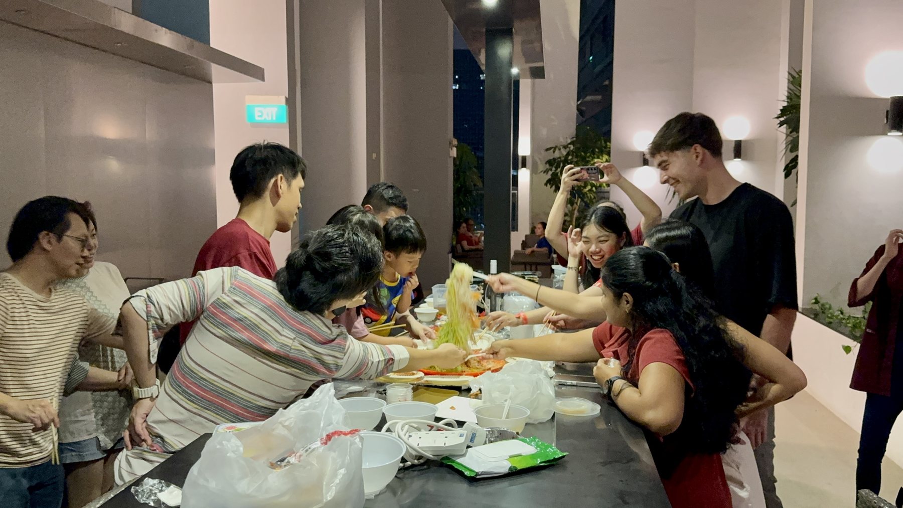 Different generations sharing a joyful lo hei meal at an RCC gathering
